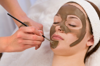 A beautiful young brunette woman having a chocolate face mask applied by a beautician